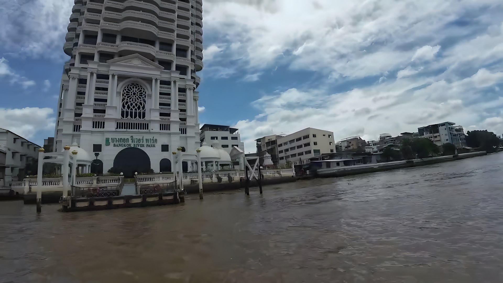 Chao Phraya Nehri kıyısındaki Bangkok River Park binası ve bulutlu gökyüzü