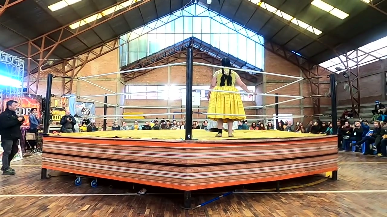 Cholita Wrestling arenasında geleneksel sarı pollera giymiş bir güreşçi