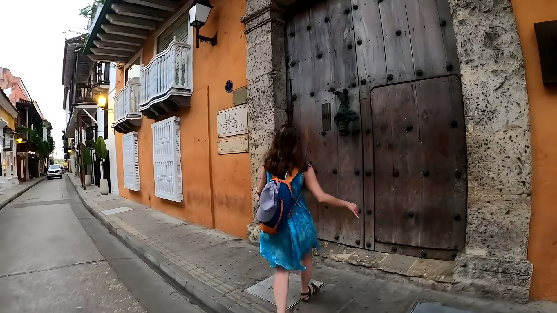 Cartagena'da turuncu kolonyal ev, beyaz ahşap balkon ve taş döşeli sokak